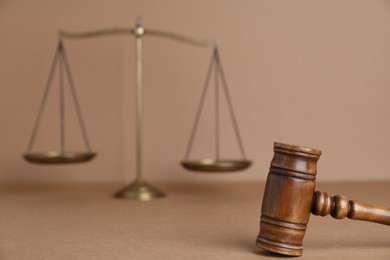 Photo of Golden scales of justice and gavel on light brown background, selective focus
