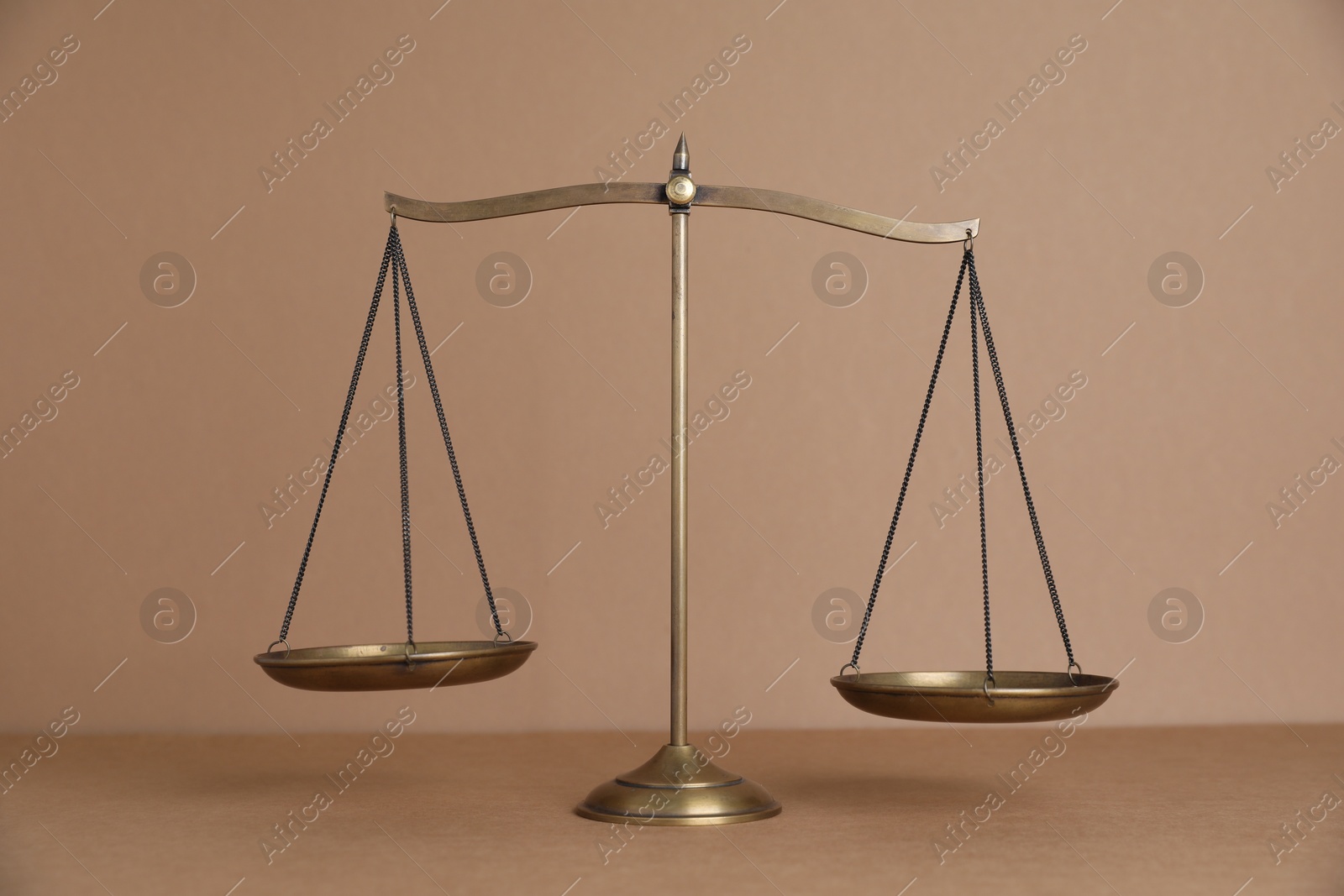 Golden scales of justice on light brown background Photo of Golden scales of justice on light brown background
