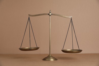 Photo of Golden scales of justice on light brown background