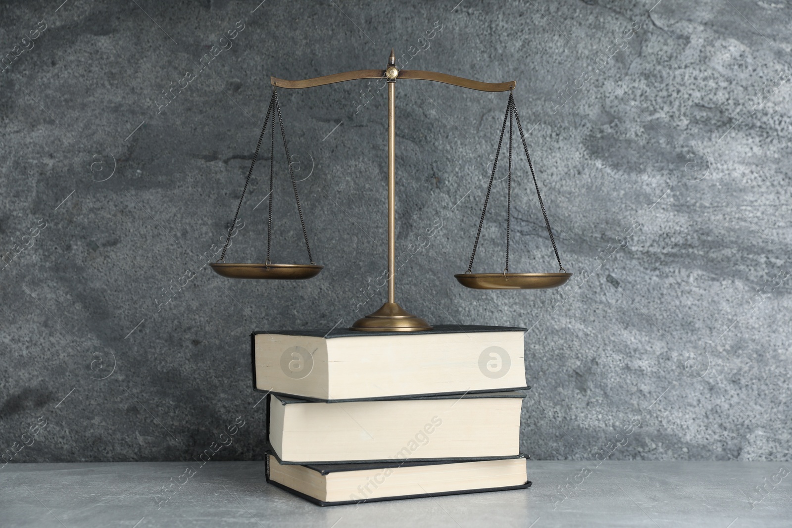 Photo of Golden scales of justice and books on grey table