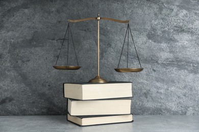 Photo of Golden scales of justice and books on grey table