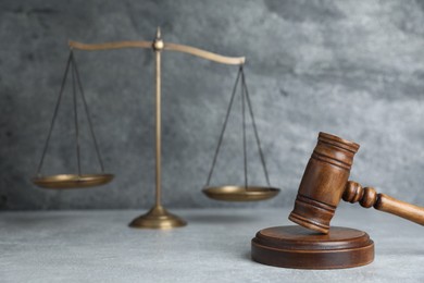 Photo of Golden scales of justice and gavel on grey table, selective focus