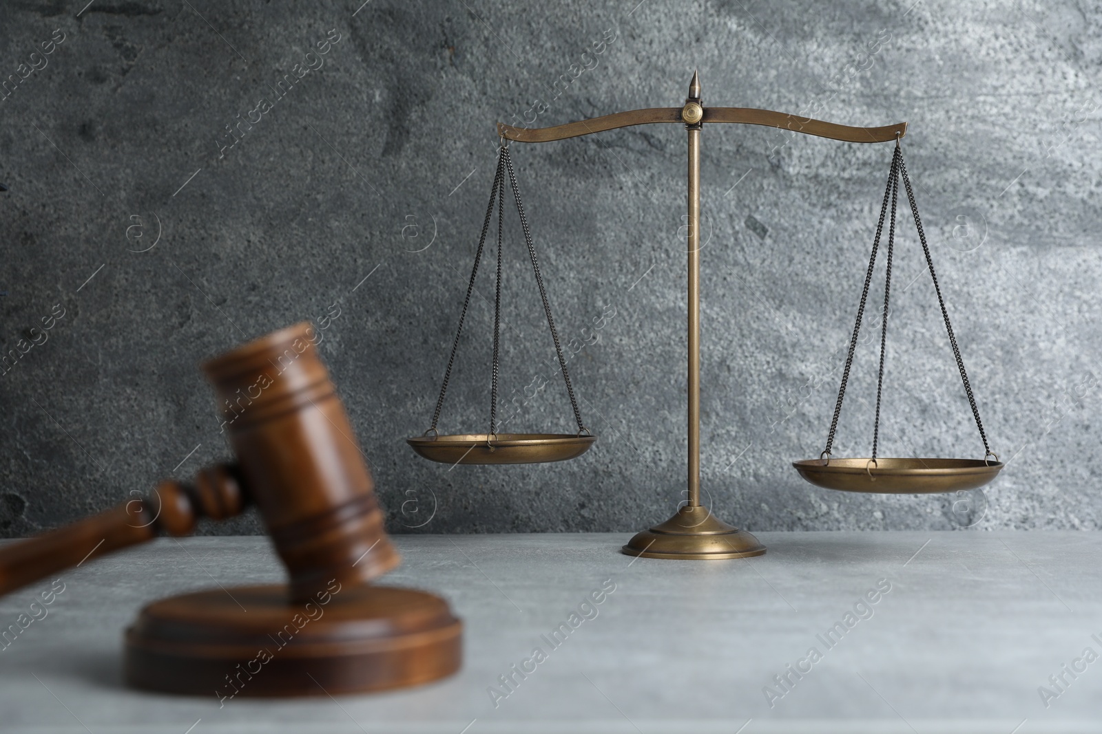 Photo of Golden scales of justice and gavel on grey table, selective focus