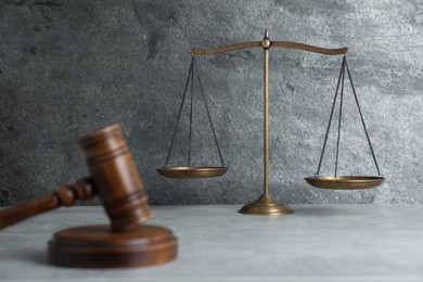 Photo of Golden scales of justice and gavel on grey table, selective focus