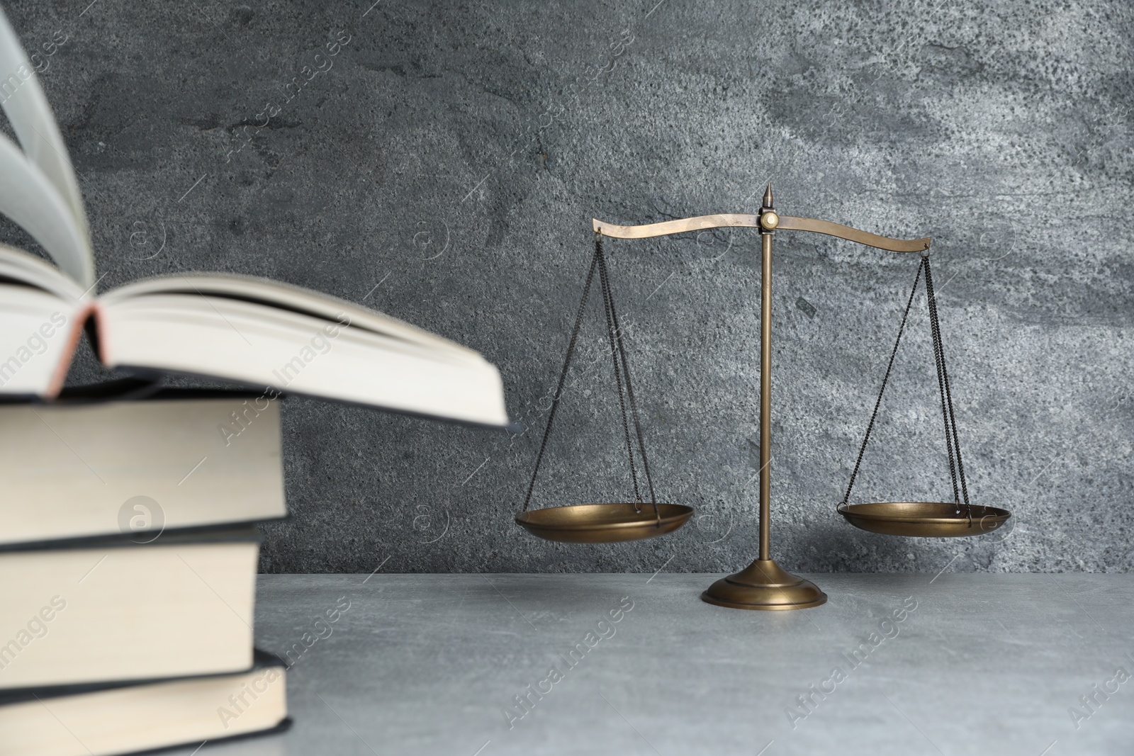 Photo of Golden scales of justice and books on grey table, selective focus