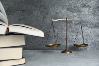 Photo of Golden scales of justice and books on grey table, selective focus