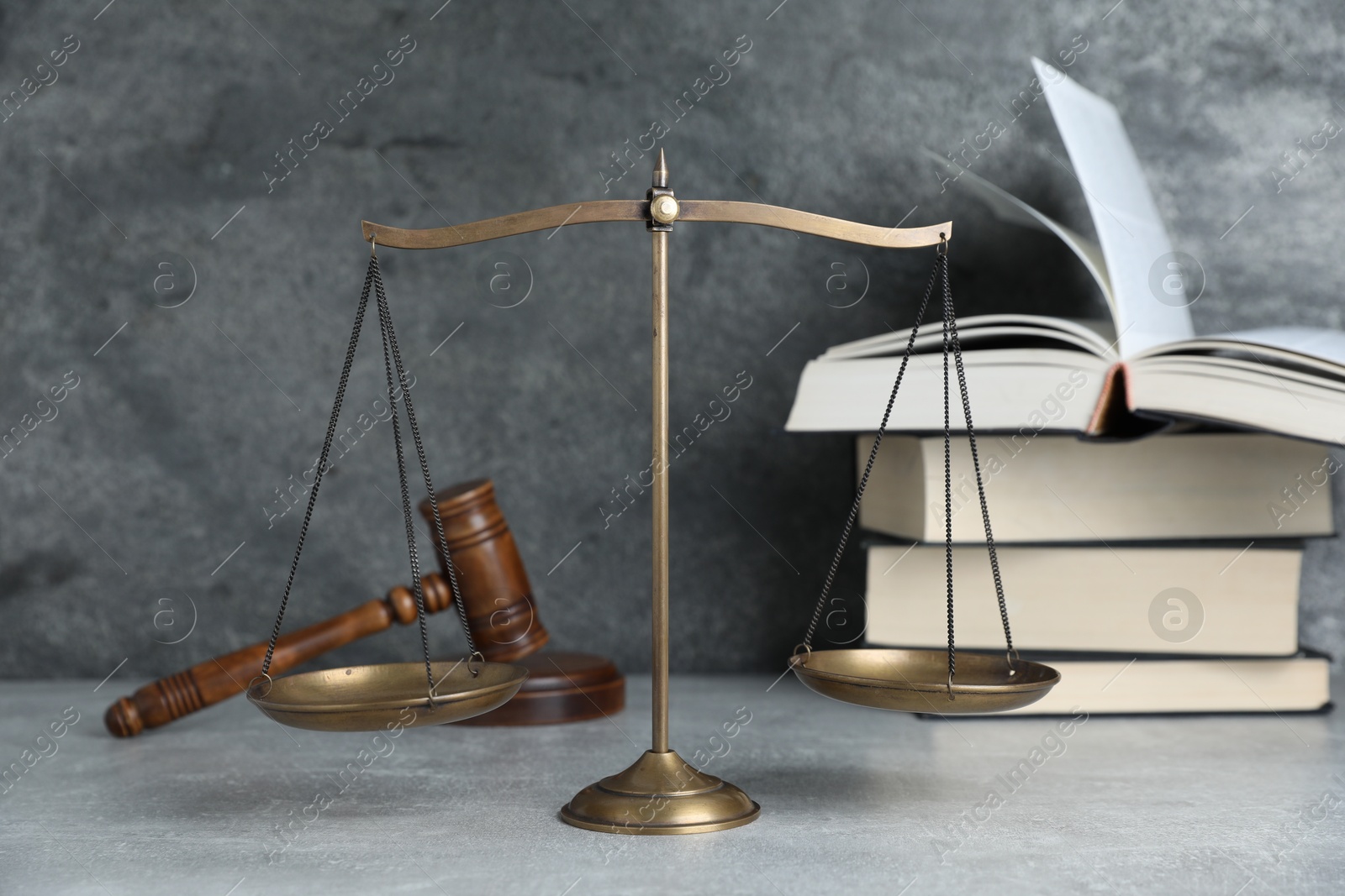 Golden scales of justice, gavel and books on grey table Photo of Golden scales of justice, gavel and books on grey table