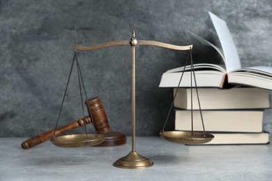 Photo of Golden scales of justice, gavel and books on grey table