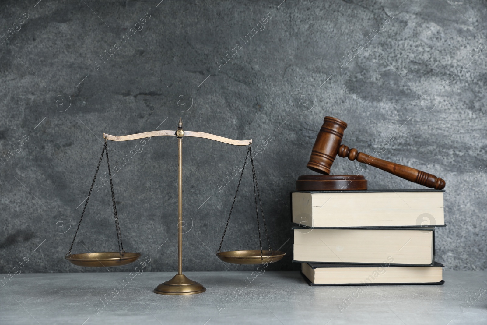 Photo of Golden scales of justice, gavel and books on grey table