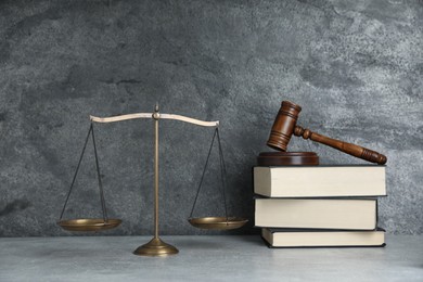 Photo of Golden scales of justice, gavel and books on grey table