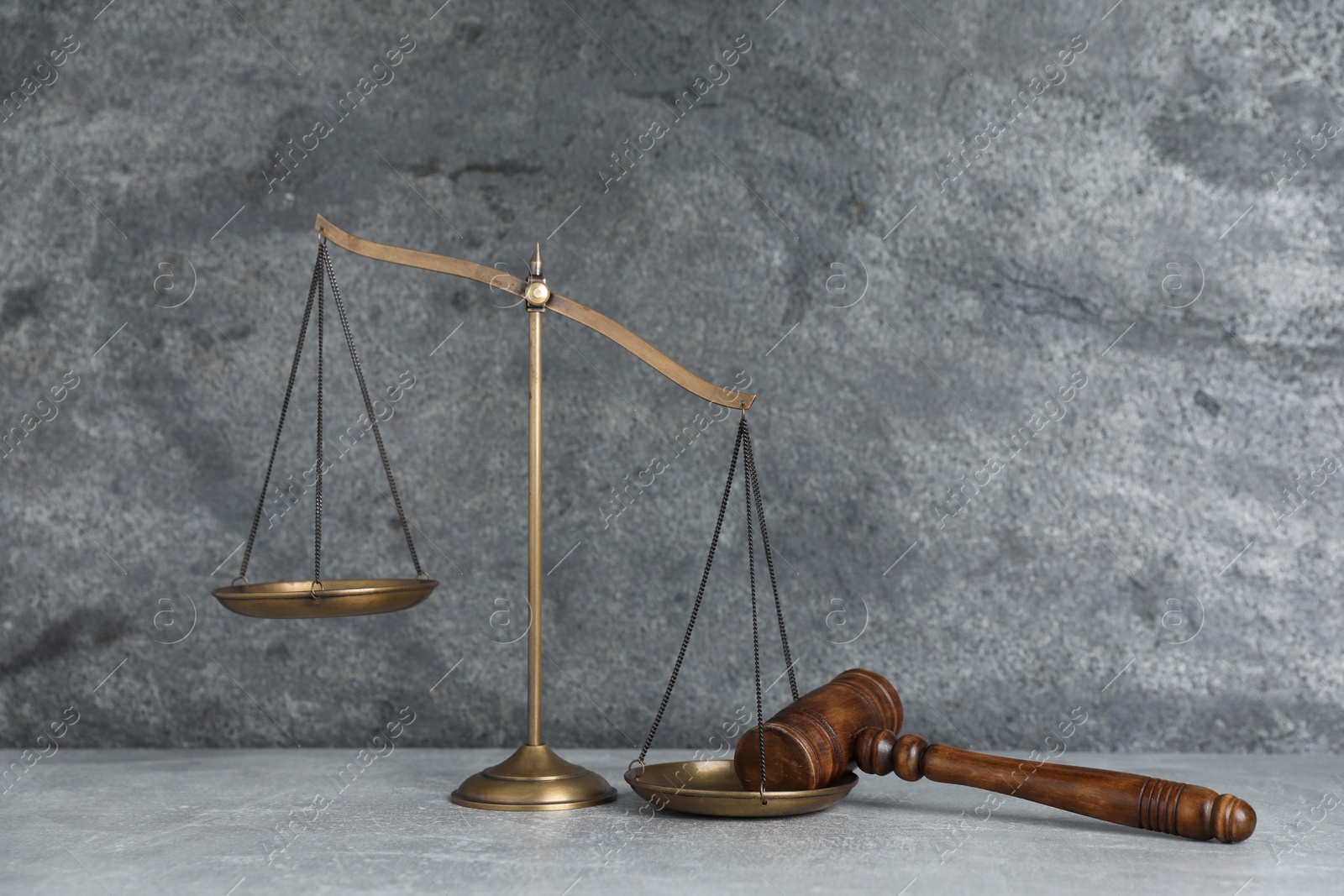 Photo of Golden scales of justice and gavel on grey table