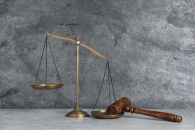 Photo of Golden scales of justice and gavel on grey table