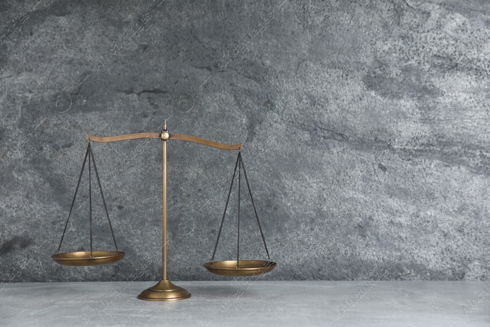 Photo of Golden scales of justice on grey table, space for text