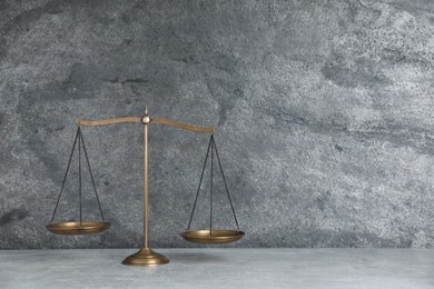 Photo of Golden scales of justice on grey table, space for text
