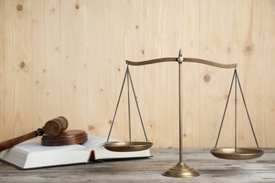 Photo of Golden scales of justice, gavel and book on wooden table