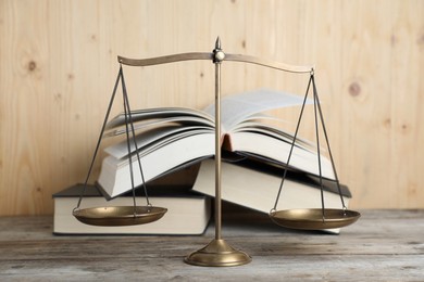 Photo of Golden scales of justice and books on wooden table