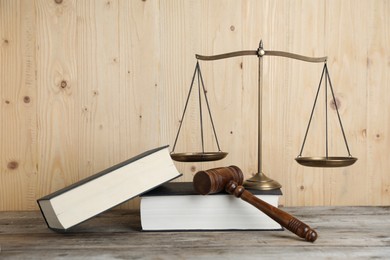 Photo of Golden scales of justice, gavel and books on wooden table