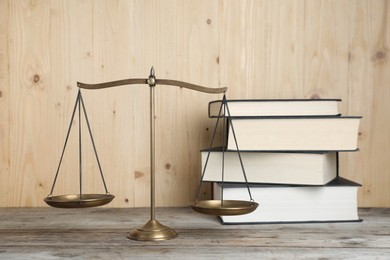 Photo of Golden scales of justice and books on wooden table