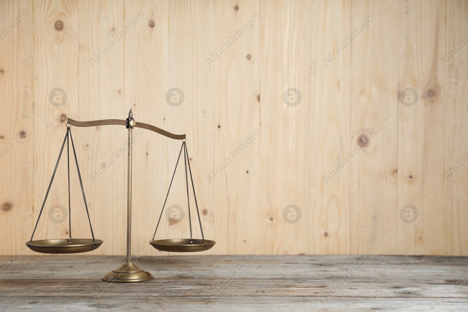 Photo of Golden scales of justice on wooden table, space for text