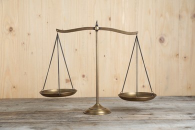 Photo of Golden scales of justice on wooden table