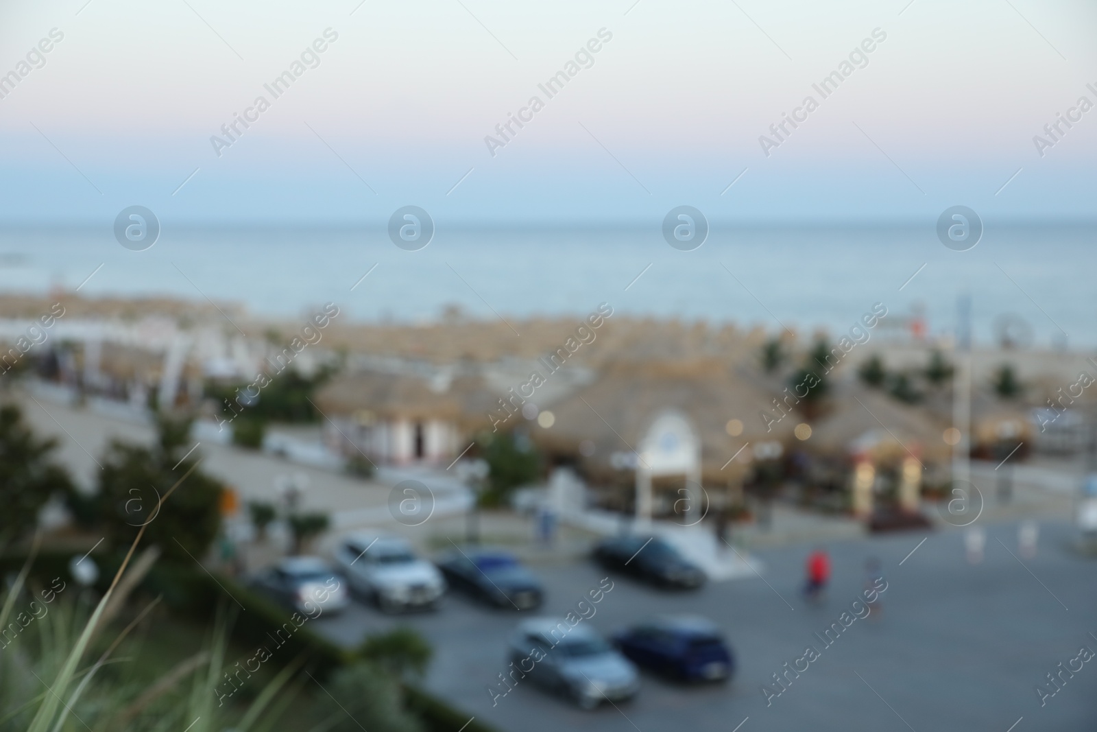 Photo of Luxury area with parked cars in resort near sea at sunset, blurred view