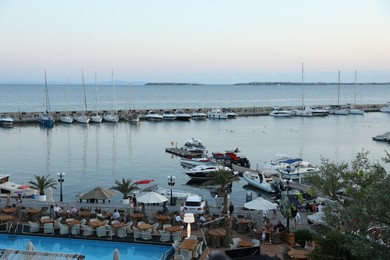 Photo of Sveti Vlas, Bulgaria - July 11, 2025: Luxury resort with swimming pool and outdoor restaurant near sea with moored boats at sunset