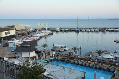 Photo of Sveti Vlas, Bulgaria - July 11, 2025: Luxury resort with swimming pool and outdoor restaurant near sea with moored boats at sunset