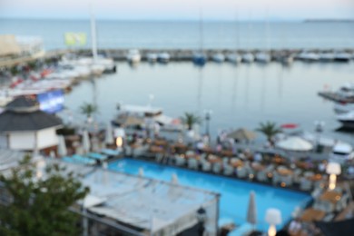 Photo of Luxury resort with swimming pool and outdoor restaurant near sea, blurred view