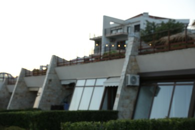 Photo of Luxury hotel building and green bushes outdoors, blurred view