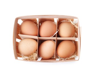 Photo of Raw chicken eggs in wooden egg tray isolated on white, top view