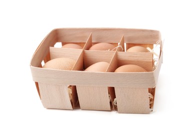 Photo of Raw chicken eggs in wooden egg tray isolated on white
