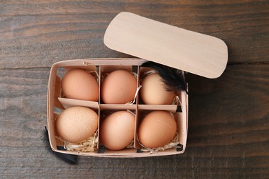 Photo of Raw chicken eggs in egg tray on wooden table, top view