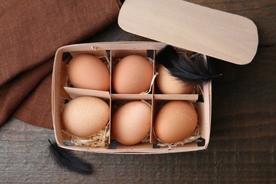 Photo of Raw chicken eggs in egg tray on wooden table, top view