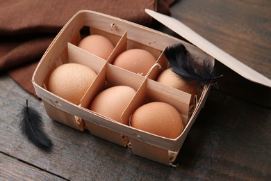 Photo of Raw chicken eggs in egg tray on wooden table, closeup