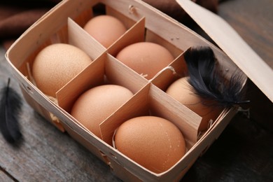 Photo of Raw chicken eggs in egg tray on wooden table, closeup