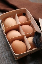 Photo of Raw chicken eggs in egg tray on wooden table, closeup