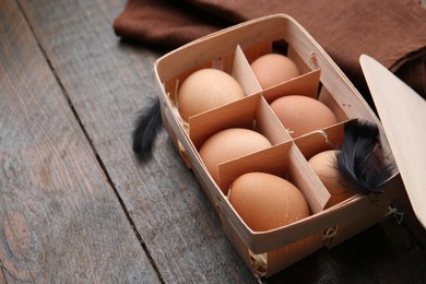 Photo of Raw chicken eggs in egg tray on wooden table, closeup. Space for text