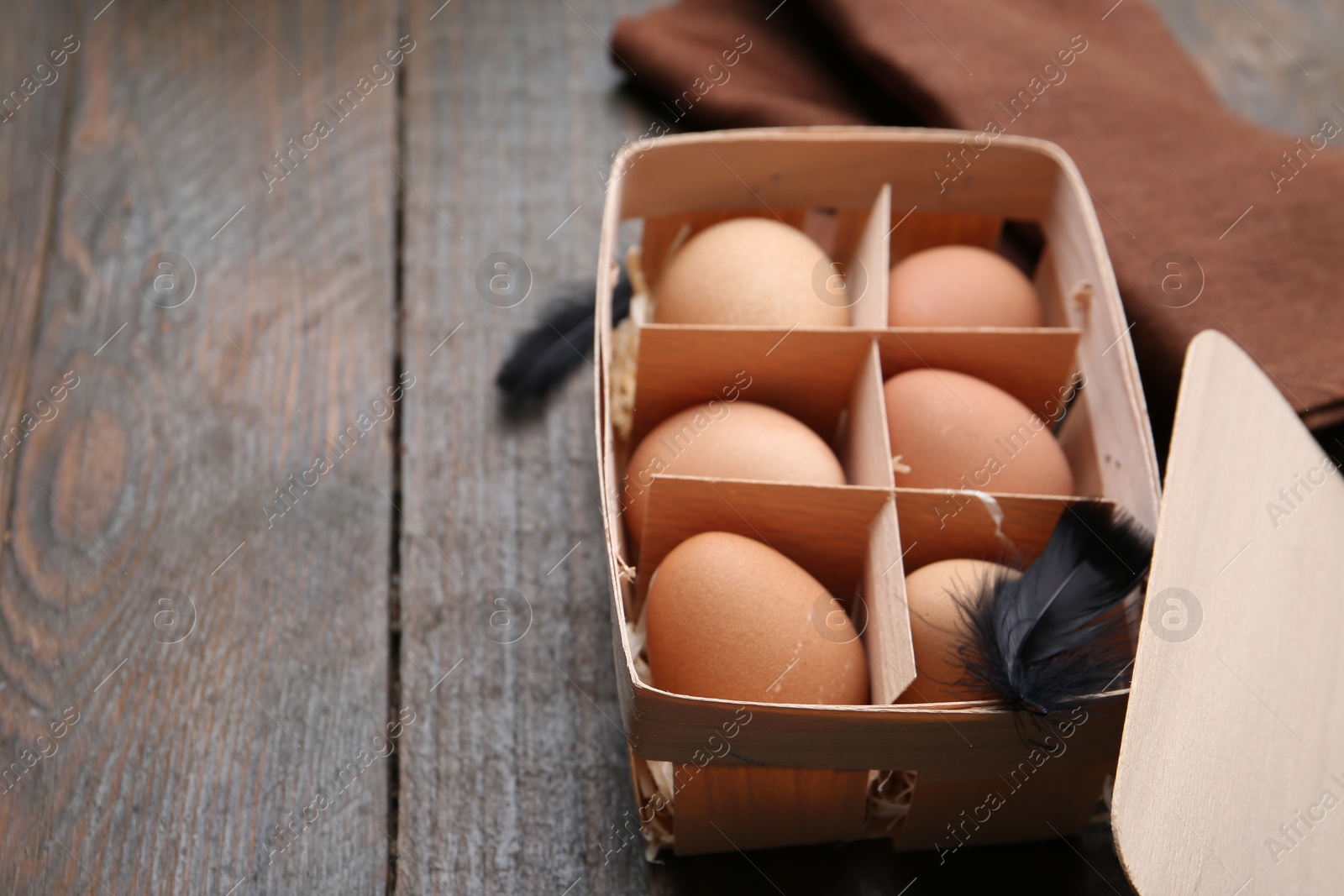 Photo of Raw chicken eggs in egg tray on wooden table, closeup. Space for text