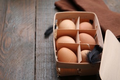 Photo of Raw chicken eggs in egg tray on wooden table, closeup. Space for text