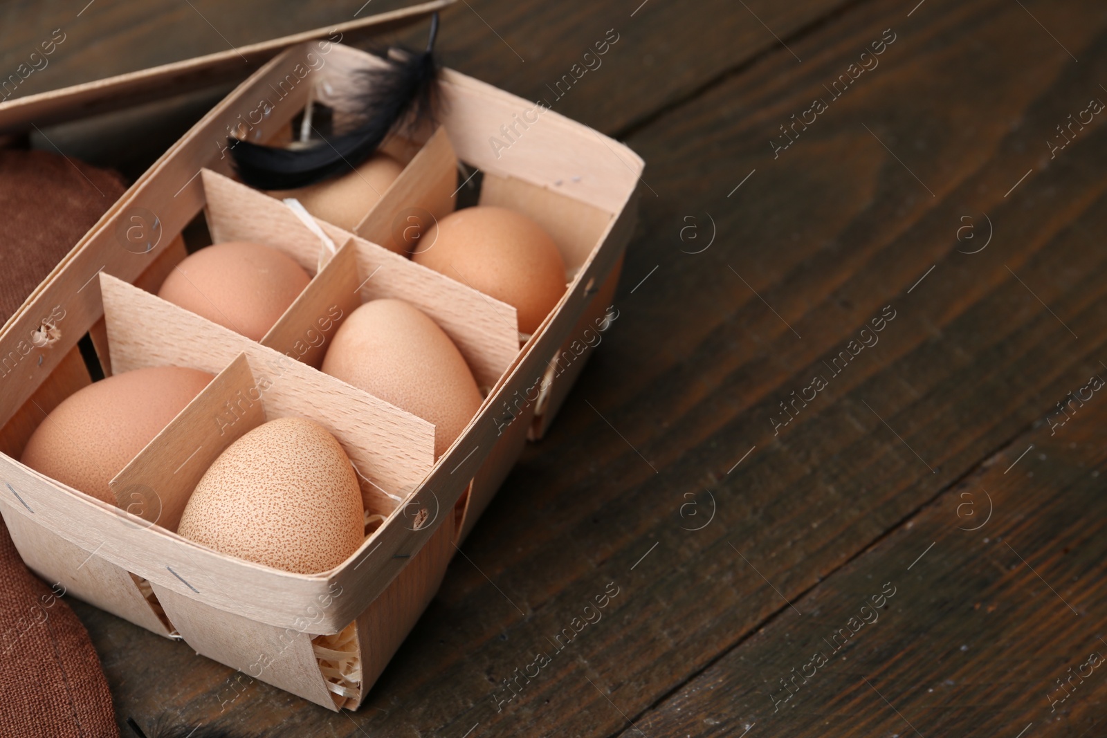 Photo of Raw chicken eggs in egg tray on wooden table, closeup. Space for text