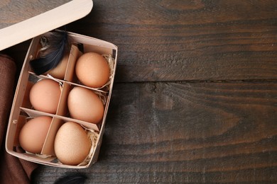 Photo of Raw chicken eggs in egg tray on wooden table, top view. Space for text