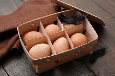 Photo of Raw chicken eggs in egg tray on wooden table, closeup