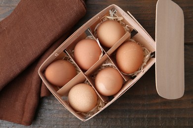 Photo of Raw chicken eggs in egg tray on wooden table, top view