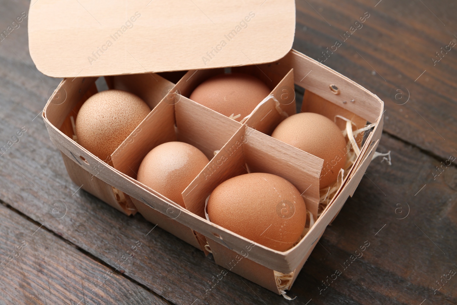 Photo of Raw chicken eggs in egg tray on wooden table, closeup
