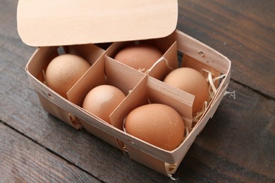 Photo of Raw chicken eggs in egg tray on wooden table, closeup