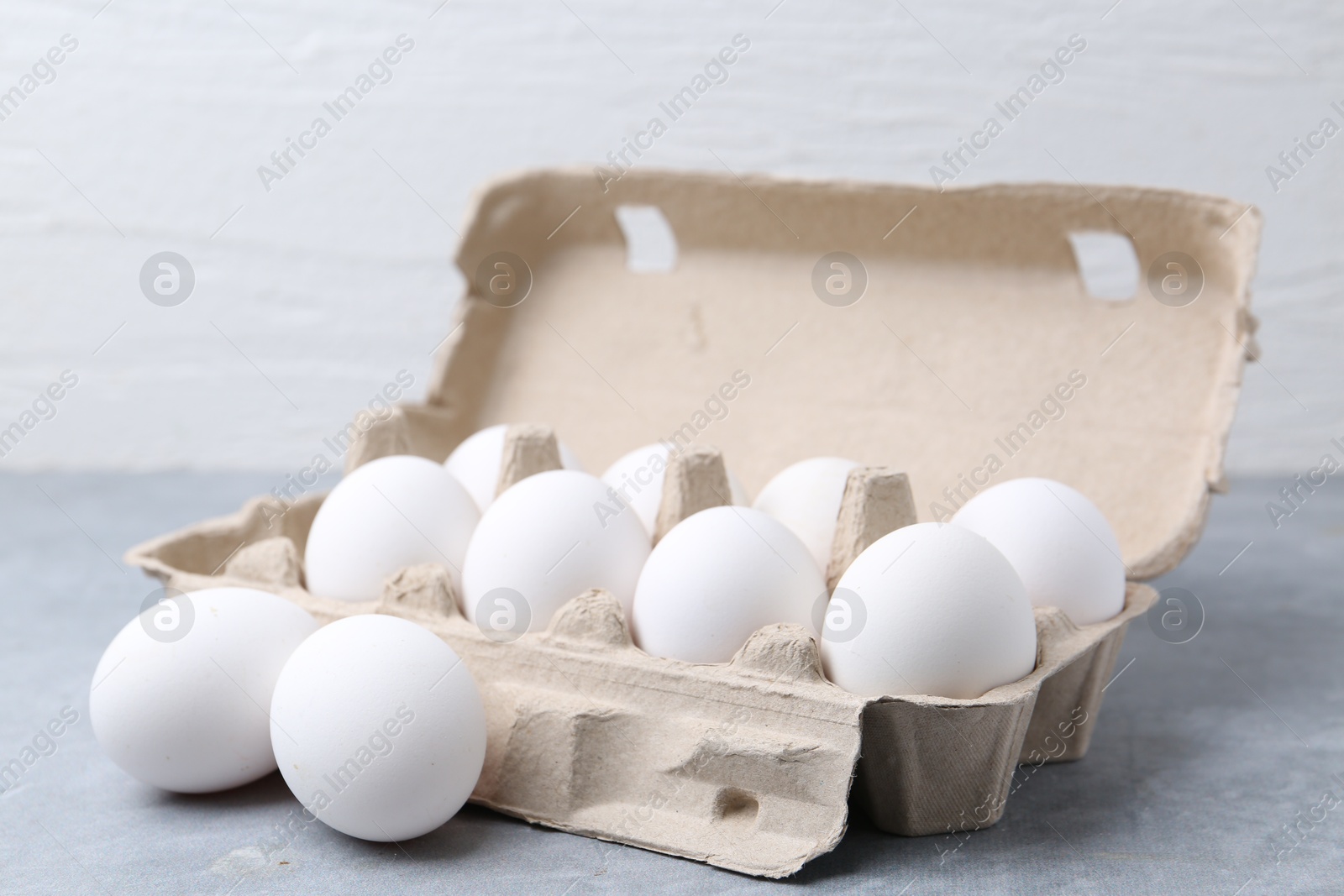 Photo of Raw chicken eggs in egg carton on grey table, closeup