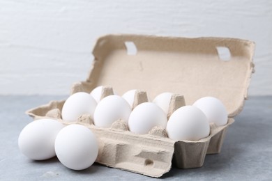 Photo of Raw chicken eggs in egg carton on grey table, closeup