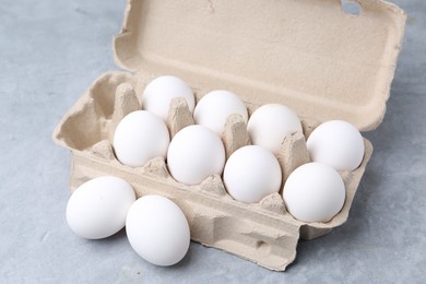 Photo of Raw chicken eggs in egg carton on grey table, closeup