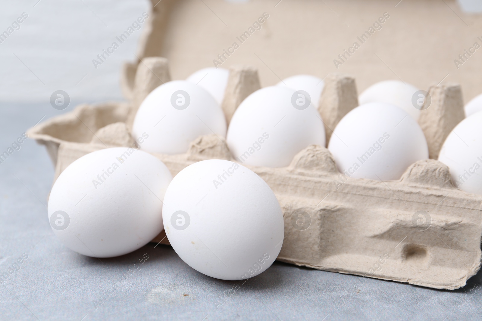 Photo of Raw chicken eggs in egg carton on grey table, closeup