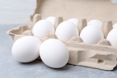 Photo of Raw chicken eggs in egg carton on grey table, closeup